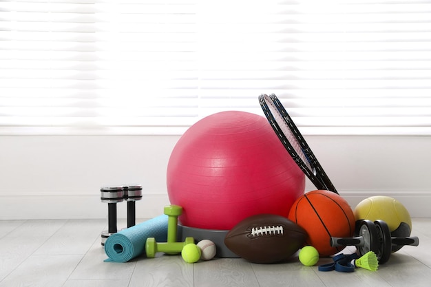Foto conjunto de diferentes equipamentos esportivos no chão branco dentro de casa