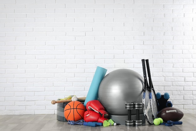 Foto conjunto de diferentes equipamentos esportivos no chão perto da parede de tijolos brancos