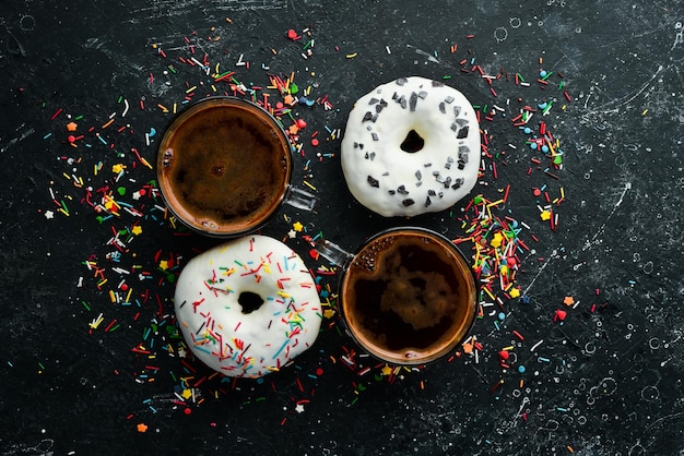 Conjunto de donuts coloridos doces com uma xícara de café em uma mesa de pedra preta Vista superior Flat Lay