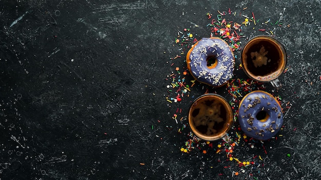 Conjunto de donuts coloridos doces com uma xícara de café em uma mesa de pedra preta Vista superior Flat Lay