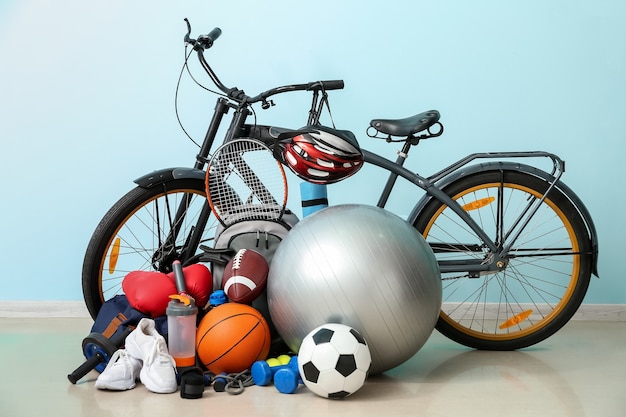 Foto conjunto de equipamentos esportivos com bicicleta perto da parede colorida