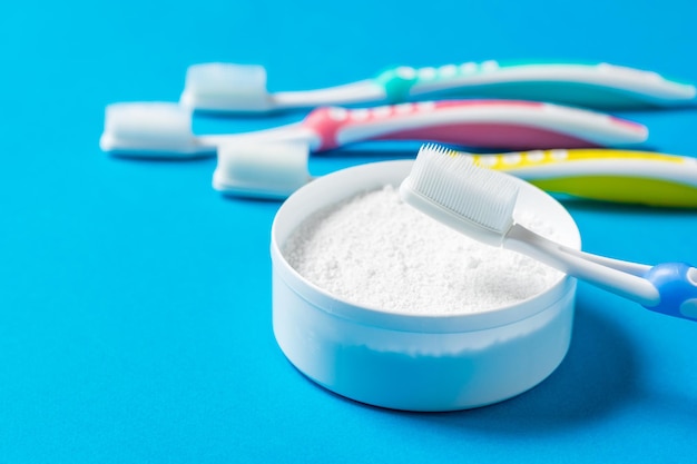 Conjunto de escovas de dente de silicone e pó de limpeza dental em um fundo azul. Significa cuidar da cavidade oral.