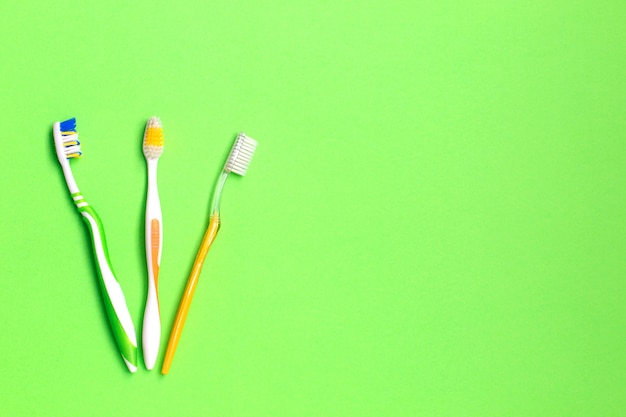 Conjunto de escovas de dentes diferentes sobre fundo verde.