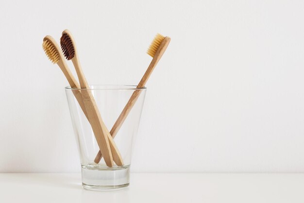 Conjunto de escovas de dentes naturais em vidro na mesa no banheiro