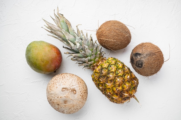 Conjunto de frutas exóticas e tropicais, abacaxi e coco, no fundo da mesa de pedra branca, vista de cima plana