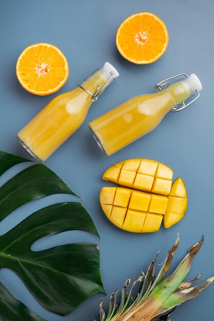 Conjunto de frutas tropicais frescas suculentas maduras, em fundo de verão texturizado azul, vista superior plana lay