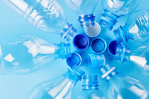 Conjunto de garrafas de água de tipo diferente vazias isoladas em fundo azul, vista superior. Conceito de produção e processamento de plástico