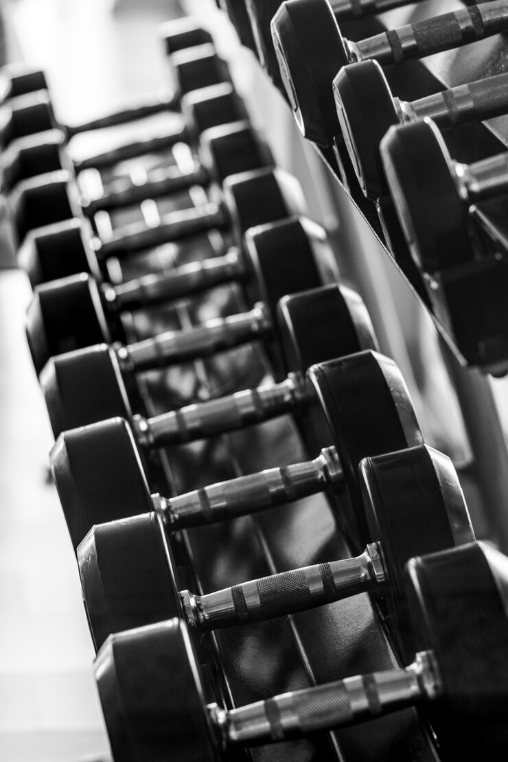 Foto conjunto de halteres preto. feche acima de muitos pesos do metal na cremalheira no fitness center do esporte, conceito do equipamento de treino com pesos. layout vertical.