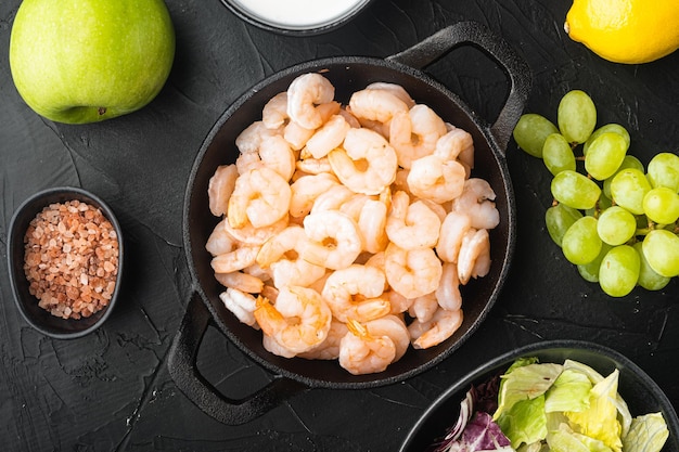 Conjunto de ingredientes de salada de camarão waldorf, com molho de maçã e uva, sobre fundo de pedra preta, vista superior plana