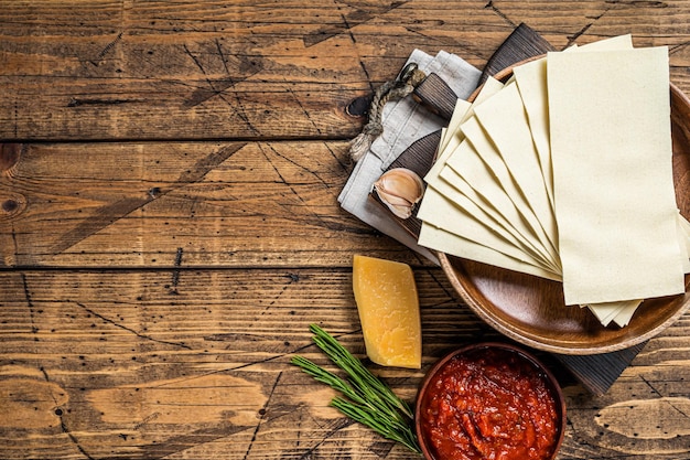 Conjunto de ingredientes para cozinhar close-up de lasanha de molho de tomate, macarrão, queijo. fundo de madeira. Vista do topo. Copie o espaço.