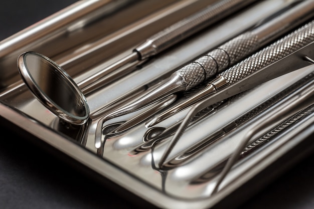 Foto conjunto de instrumentos odontológicos para tratamento dentário. ferramentas médicas em bandeja de aço inoxidável. vista de perto. profundidade superficial de campo.