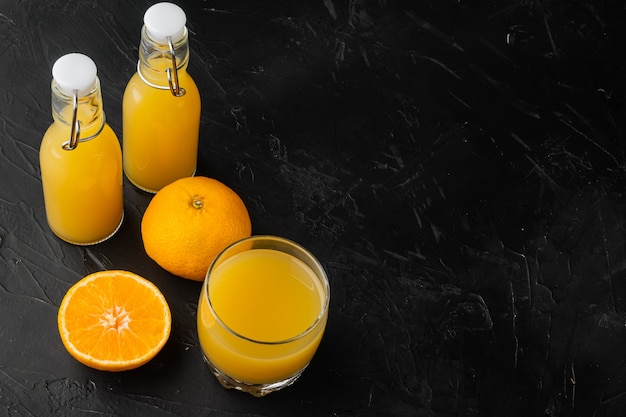 Conjunto de jarra de vidro com suco de laranja fresco, no fundo da mesa de pedra escura e preta, com espaço de cópia para o texto