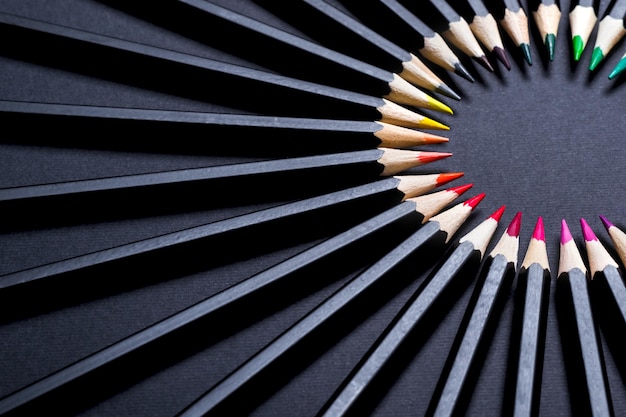 Conjunto de lápis de cor dispostos em círculo sobre fundo preto. cenário de papelaria para seu projeto.