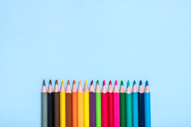 Foto conjunto de lápis de cor isolados em fundo azul vista superior conceito de artesanato de educação plana leiga