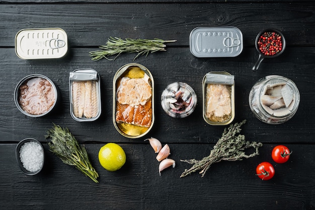 Conjunto de latas de conservas com diferentes tipos de peixe definido, em mesa de madeira preta