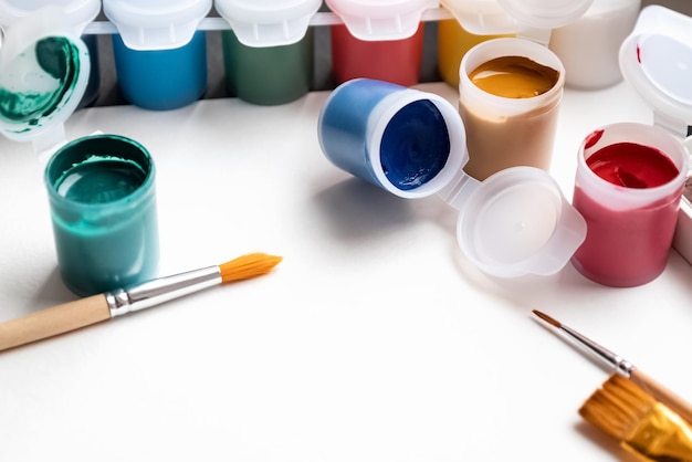 Conjunto de latas de tinta colorida e pincéis para pintar em fundo de papel Conceito de hobby e educação