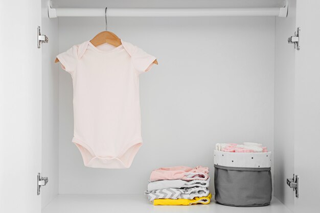 Conjunto de macacões de bebê para uma menina recém-nascida e um menino em cabides no guarda-roupa branco. maternidade, limpar o guarda-roupa dos filhos em casa. conceito de moda mínimo.