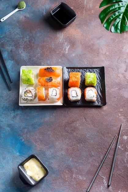 Conjunto de maki roll e folhas verdes palm na mesa de pedra.