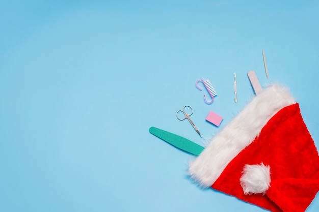 Conjunto de manicure em um chapéu de Papai Noel vermelho sobre um azul