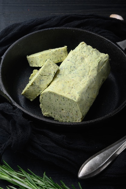 Conjunto de manteiga de leite verde com ervas, na mesa de madeira preta