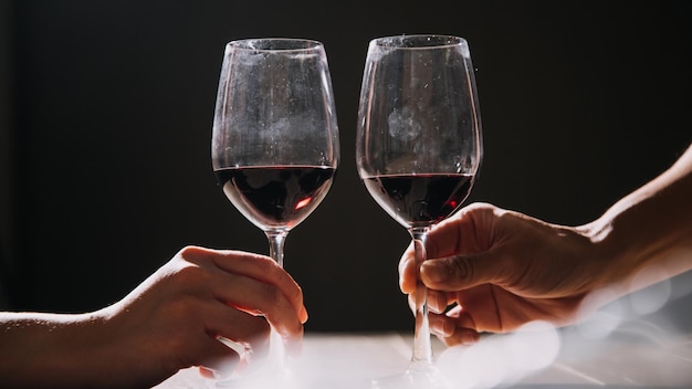 Conjunto de mãos segurando um copo de vinho tinto isolado no fundo preto