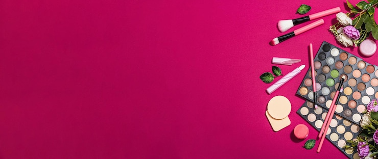 Foto conjunto de maquiagem com paletas de sombras coloridas, pincéis, esponjas e flores fundo de cor magenta viva da moda primavera conceito cosmético festivo formato de banner plano