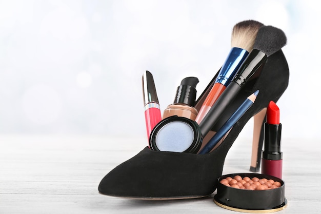 Conjunto de maquiagem com pincéis de sapato de mulher negra e cosméticos em fundo branco