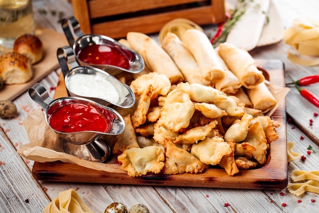 Conjunto de mini chebureks e rolinhos primavera com molhos