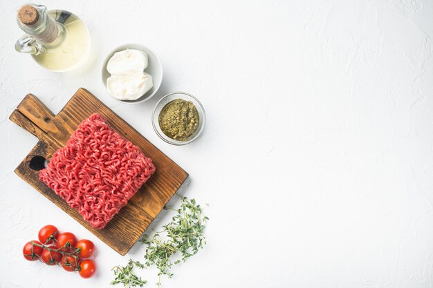 Conjunto de mistura de carne picada para almôndegas e ingredientes, em mesa de pedra branca, vista de cima plano