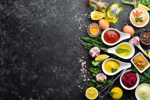 Conjunto de molhos coloridos e especiarias em fundo de pedra preta Molhos tradicionais para carne e peixe