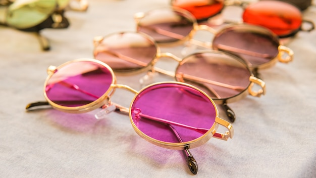Conjunto de óculos de sol coloridos à venda em uma loja. Óculos de sol diferentes em fundo de cor clara. Óculos de verão. Coleção de moda