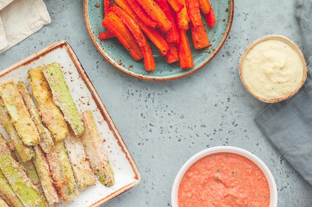 Conjunto de palitos de legumes assados de abobrinha e cenoura com molho e homus Comida vegetariana saudável Vista superior plana