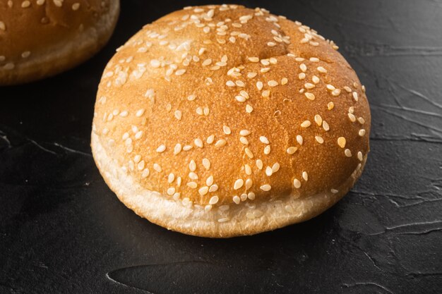 Conjunto de pão de sanduíche com sementes de gergelim, na mesa de pedra preta