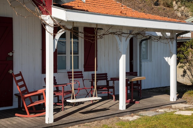 Conjunto de pátio de madeira, incluindo mesa e cadeiras vermelhas, bem como um balanço em um deck de madeira no jardim ensolarado