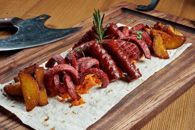 Conjunto de petiscos de cerveja - salsichas assadas, couve cozida e batatas em uma placa de madeira. Fotografia de alimentos