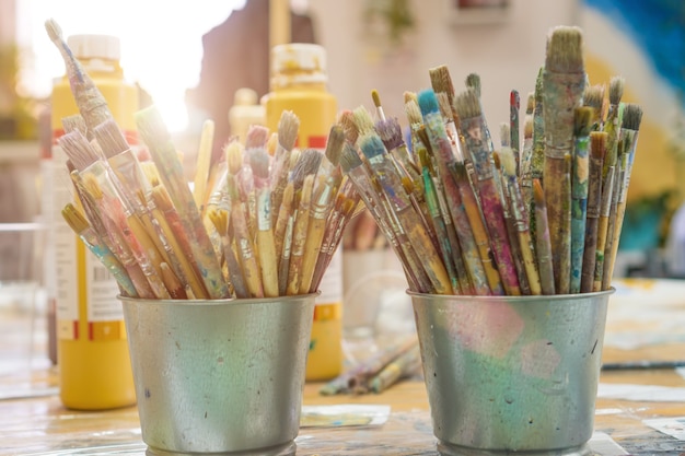 Conjunto de pincéis multicoloridos na xícara. Pincéis e tintas para desenho. Interior da escola de arte para desenhar crianças. Conceito de criatividade e pessoas.