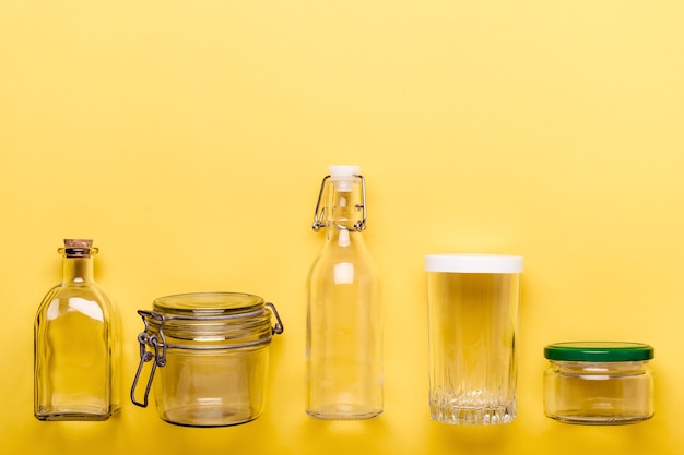Conjunto de potes de vidro e garrafas em fundo amarelo. conceito de plástico zero.