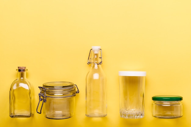 Conjunto de potes de vidro e garrafas em fundo amarelo. Conceito de plástico zero.