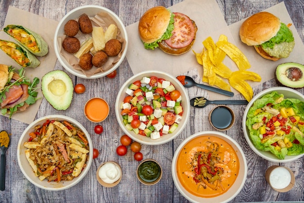 Foto conjunto de pratos saladas comida latina hambúrgueres abacates e tomate cereja em uma mesa marrom