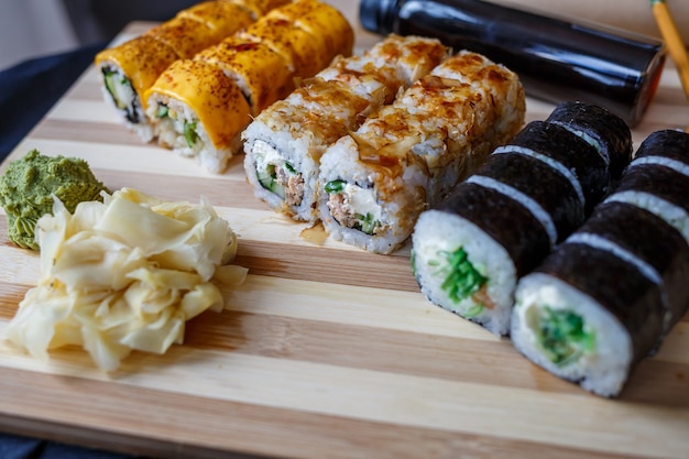 Conjunto de pratos tradicionais japoneses. Rolinhos de sushi, nigiri, salmão cru, arroz, cream cheese, abacate, gengibre em conserva.