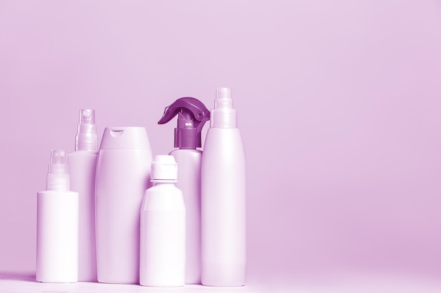 Conjunto de produtos cosméticos em recipientes rosa e cinza sobre fundo claro.
