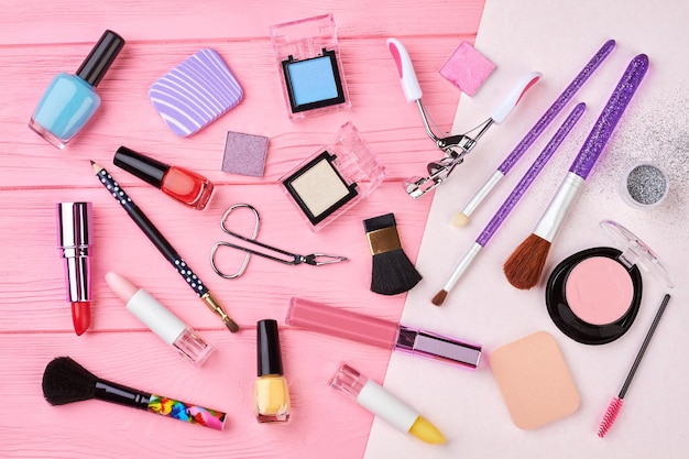 Conjunto de produtos cosméticos femininos, vista superior. Cosméticos de maquiagem, pincéis e outros itens essenciais em fundo rosa. Postura plana de itens de beleza da moda.