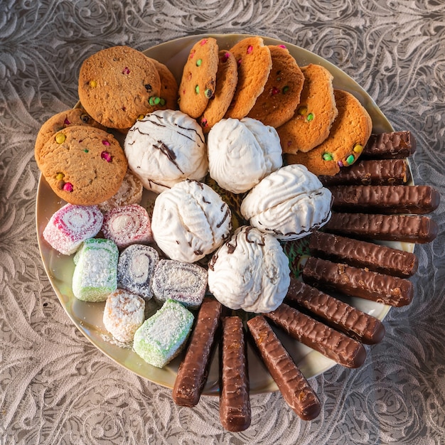 Conjunto de produtos de confeitaria. Doces no prato - zéfiro, marmelada, biscoitos e palitos de chocolate. Foto de stock de vista superior