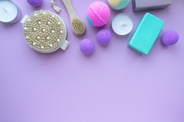 Conjunto de produtos de spa. Bombas de banho, sabonete e escovas de massagem em fundo roxo, espaço para texto