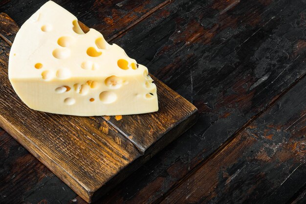 Conjunto de queijo Maasdam, na velha mesa de madeira escura, com espaço de cópia para o texto