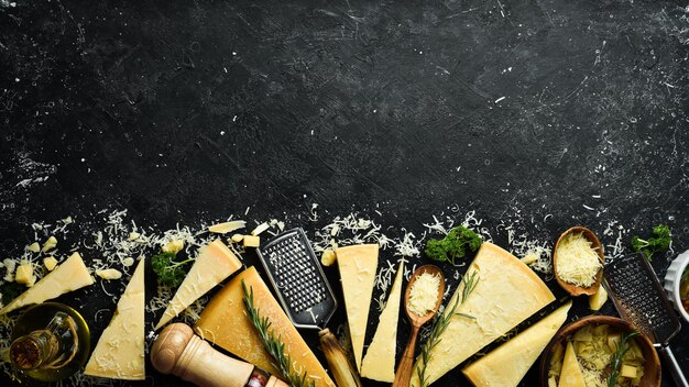 Conjunto de queijos duros com facas de queijo em fundo de pedra preta Parmesão Vista superior Espaço livre para o seu texto