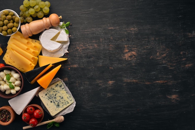 Conjunto de queijos Queijo azul Suluguni mussarela maasdam queijo brie Vista superior Em um fundo preto de madeira Espaço para cópia gratuita