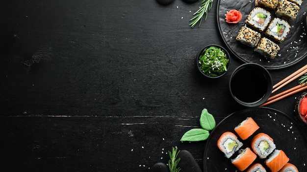 Foto conjunto de rolos de sushi com gengibre, wasabi e molho de soja em um fundo de pedra preta. cozinha tradicional japonesa. vista do topo. estilo rústico.