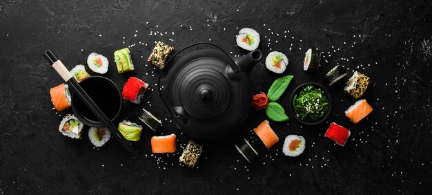 Conjunto de rolos de sushi com gengibre wasabi e molho de soja em um fundo de pedra preta Cozinha tradicional japonesa Vista superior Estilo rústico