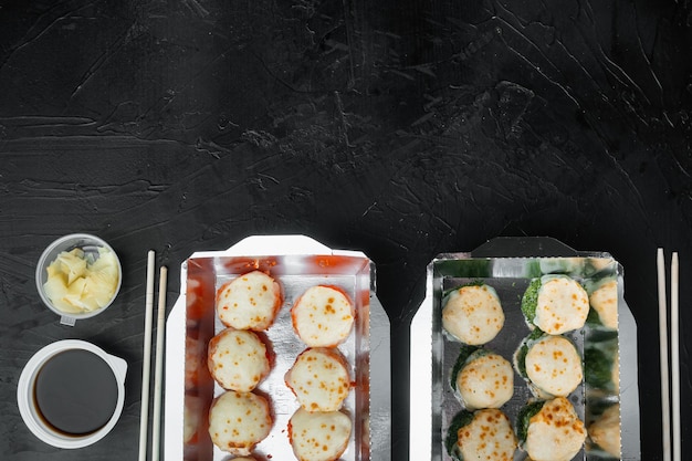 Conjunto de rolos de sushi em conjunto de caixa de entrega de comida, em fundo de pedra preta, vista de cima plana, com copyspace e espaço para texto